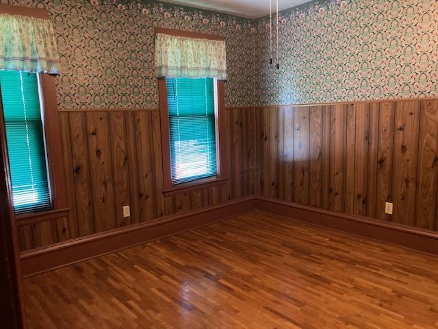 201 Cherry St, Lowry, MN 56349 - empty room with wallpapered walls, a wainscoted wall, wood finished floors, and wooden walls
