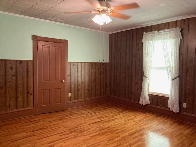 201 Cherry St, Lowry, MN 56349 - empty room featuring wood walls, a ceiling fan, light wood-style flooring, a wainscoted wall, and crown molding