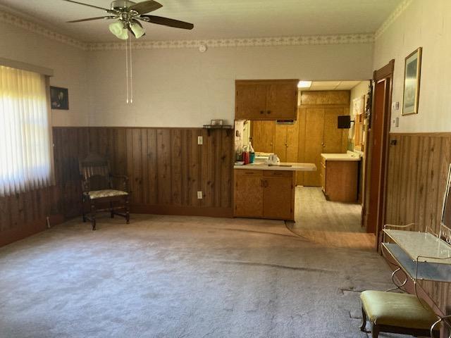 201 Cherry St, Lowry, MN 56349 - sitting room with wood walls, a ceiling fan, a wainscoted wall, and light colored carpet