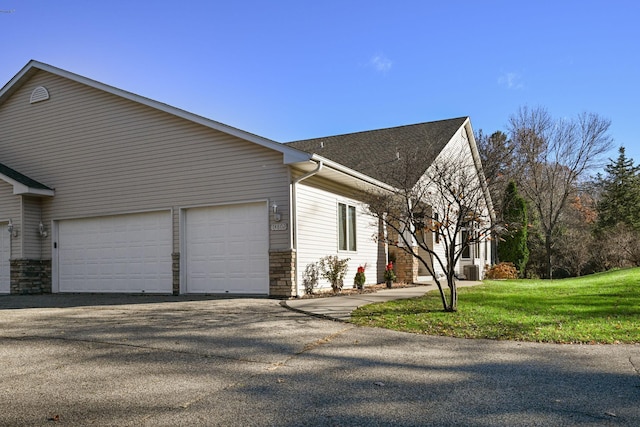 14802 Margaret Pl, Minnetonka, MN 55345 - view of home's exterior featuring an attached garage, driveway, stone siding, and a yard