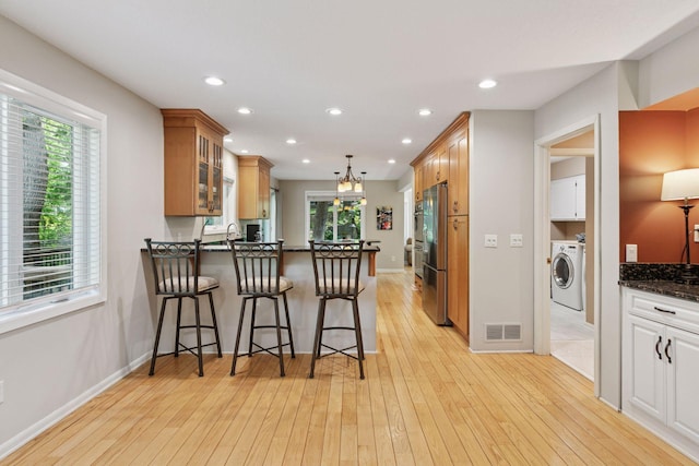 8155 134th St W, Apple Valley, MN 55124 - kitchen featuring washer / clothes dryer, freestanding refrigerator, a peninsula, glass insert cabinets, and light wood-style flooring