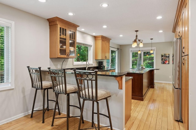 8155 134th St W, Apple Valley, MN 55124 - kitchen with a peninsula, freestanding refrigerator, recessed lighting, light wood finished floors, and a breakfast bar