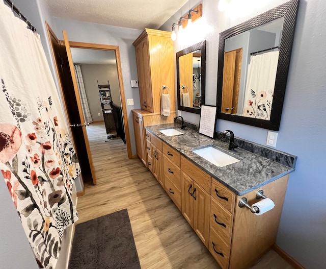 211 5th St NE, Barnesville, MN 56514 - full bath with wood finished floors, double vanity, baseboards, and a textured ceiling