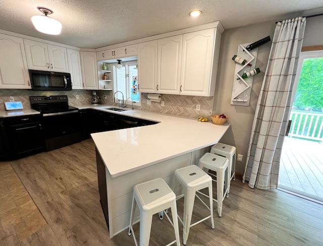 211 5th St NE, Barnesville, MN 56514 - kitchen with black appliances, a sink, white cabinets, open shelves, and light wood-style floors