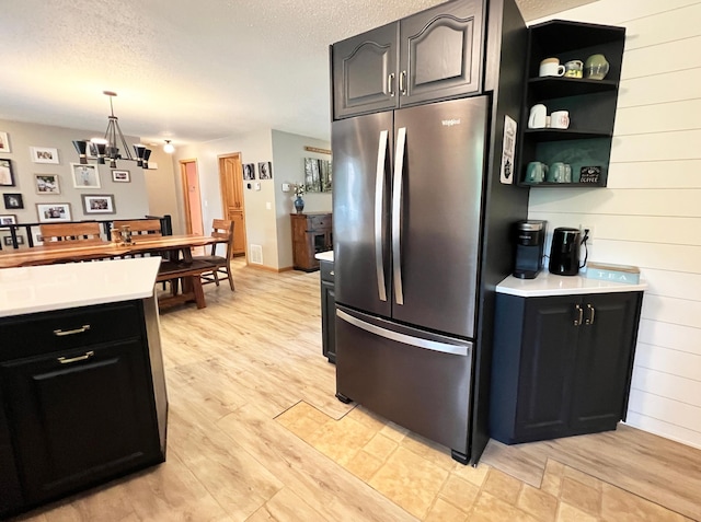 211 5th St NE, Barnesville, MN 56514 - kitchen with freestanding refrigerator, light countertops, light wood-type flooring, a textured ceiling, and a chandelier