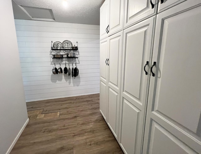 211 5th St NE, Barnesville, MN 56514 - hallway featuring dark wood finished floors, a textured ceiling, baseboards, and wood walls