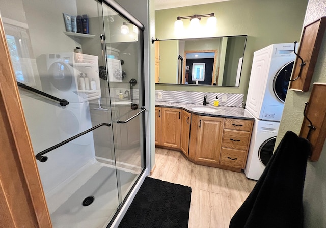 211 5th St NE, Barnesville, MN 56514 - bathroom featuring stacked washer / drying machine, a shower stall, wood finished floors, vanity, and tasteful backsplash