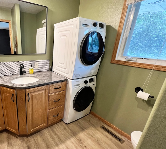 211 5th St NE, Barnesville, MN 56514 - washroom featuring stacked washer and clothes dryer, light wood finished floors, and baseboards