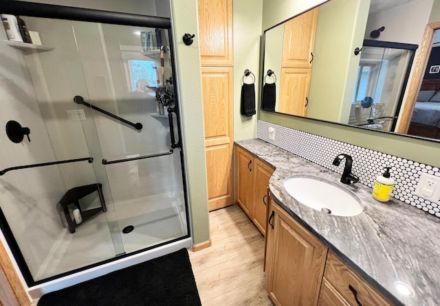 211 5th St NE, Barnesville, MN 56514 - bathroom with a shower stall, decorative backsplash, vanity, and wood finished floors