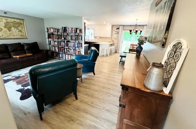 211 5th St NE, Barnesville, MN 56514 - living room with light wood-style flooring, a chandelier, and a textured ceiling
