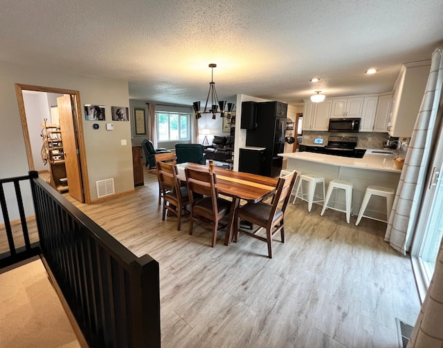 211 5th St NE, Barnesville, MN 56514 - dining space featuring light wood-style flooring, a textured ceiling, and a chandelier
