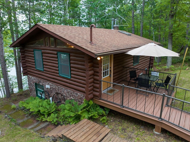 3938 State Road 77, Swiss Twp, WI 54830 - back of house featuring log exterior, roof with shingles, stone siding, a deck, and outdoor dining space