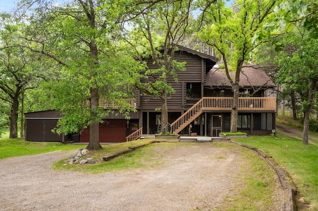21750 Elk Lake Rd NW, Elk River, MN 55330 - view of front of home with log siding, a wooden deck, dirt driveway, stairs, and a front lawn