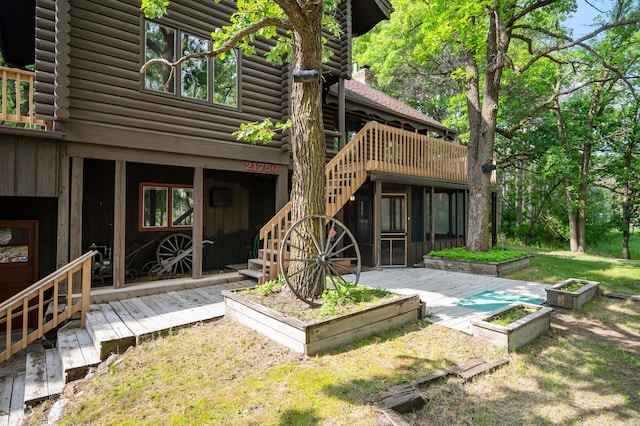 21750 Elk Lake Rd NW, Elk River, MN 55330 - rear view of house featuring log siding, a deck, a vegetable garden, and stairway