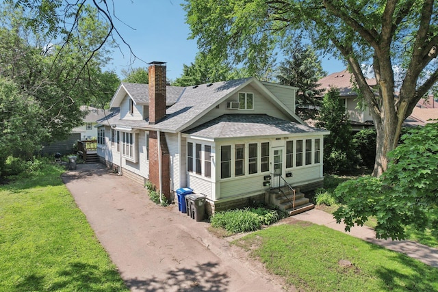 1384 Midway Pkwy, Saint Paul, MN 55108 - view of front facade with roof with shingles, a chimney, asphalt driveway, and a front lawn