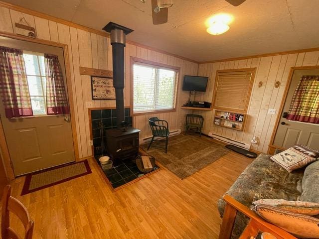 4716 Big Rice Lake Rd NE, Thunder Lake Twp, MN 56672 - living room with a wood stove, wood finished floors, a ceiling fan, crown molding, and wood walls