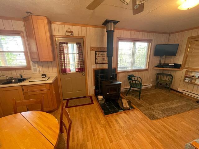 4716 Big Rice Lake Rd NE, Thunder Lake Twp, MN 56672 - kitchen with ceiling fan, a wood stove, a sink, light wood-style floors, and wood walls