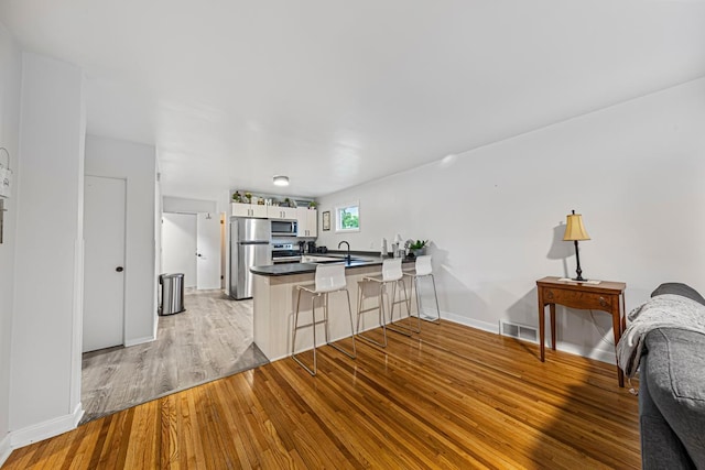 1819 4th Ave, Mankato, MN 56001 - kitchen with appliances with stainless steel finishes, a peninsula, a sink, open floor plan, and light wood-style flooring