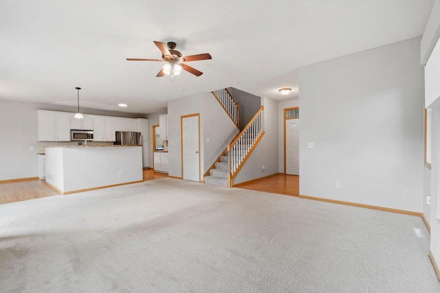 6701 Urbandale Ln N, Maple Grove, MN 55311 - unfurnished living room with light carpet, a ceiling fan, and stairs