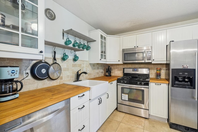 4004 Foss Rd Unit 101, Saint Anthony, MN 55421 - kitchen with stainless steel appliances, butcher block countertops, white cabinetry, tasteful backsplash, and light tile patterned flooring