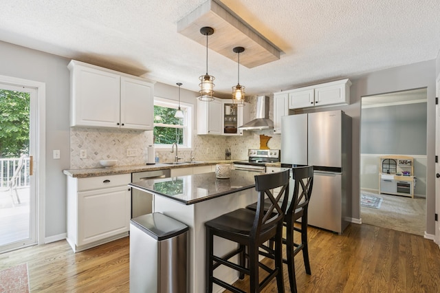 2740 Simons Dr, Chaska, MN 55318 - kitchen with wall chimney exhaust hood, appliances with stainless steel finishes, a textured ceiling, light wood finished floors, and white cabinetry