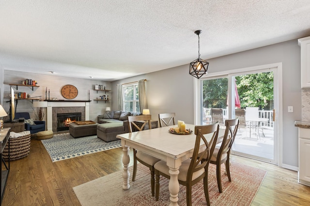 2740 Simons Dr, Chaska, MN 55318 - dining room featuring a textured ceiling, light wood-style floors, and a tiled fireplace
