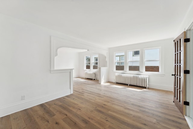 987 Dayton Ave, Saint Paul, MN 55104 - unfurnished room with radiator heating unit, wood finished floors, arched walkways, and baseboards