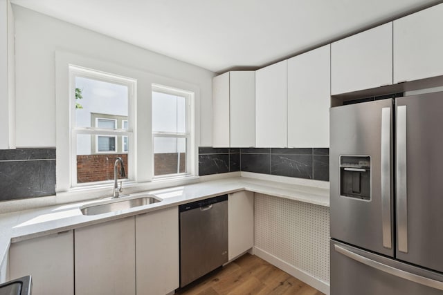 987 Dayton Ave, Saint Paul, MN 55104 - kitchen featuring appliances with stainless steel finishes, a sink, light wood-style flooring, and white cabinetry