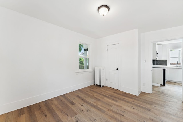 987 Dayton Ave, Saint Paul, MN 55104 - empty room featuring radiator heating unit, light wood finished floors, baseboards, and a sink