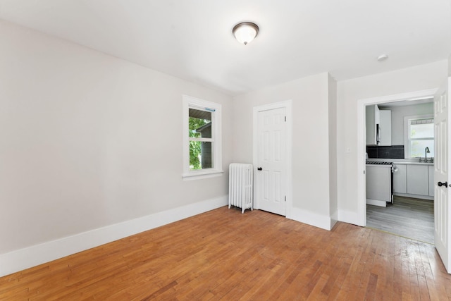 987 Dayton Ave, Saint Paul, MN 55104 - empty room featuring radiator, light wood-style floors, a sink, and baseboards