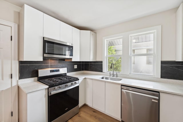 987 Dayton Ave, Saint Paul, MN 55104 - kitchen featuring appliances with stainless steel finishes, a sink, white cabinets, and decorative backsplash