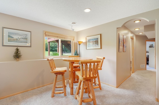 13589 Birch Rd, Rogers, MN 55374 - dining room featuring light colored carpet, arched walkways, a textured ceiling, and recessed lighting