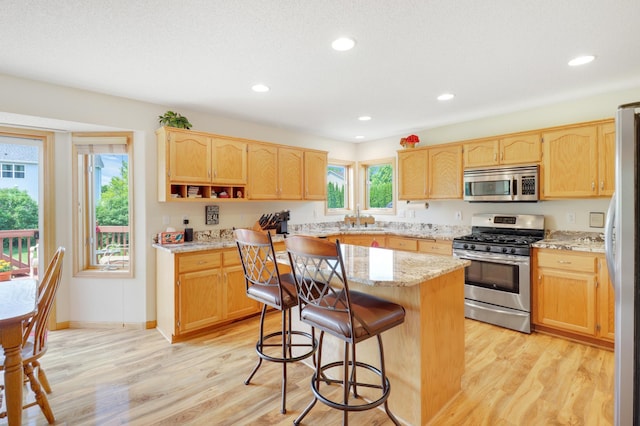 13589 Birch Rd, Rogers, MN 55374 - kitchen featuring stainless steel appliances, light brown cabinets, a kitchen bar, light wood-style flooring, and recessed lighting