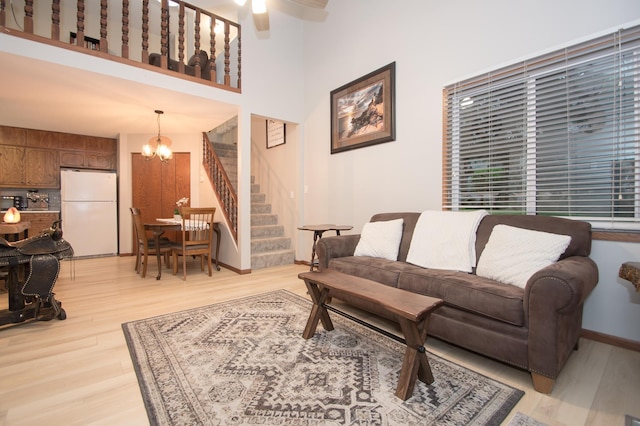 544 Auburn Pl NW Unit H, Elk River, MN 55330 - living area with stairway, a chandelier, light wood-style floors, a ceiling fan, and a towering ceiling