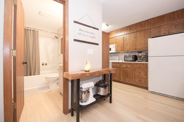 544 Auburn Pl NW Unit H, Elk River, MN 55330 - kitchen featuring white appliances, brown cabinetry, light wood-style floors, and decorative backsplash