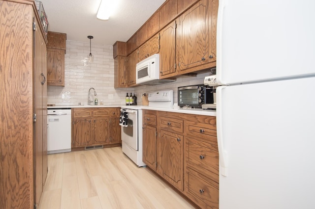544 Auburn Pl NW Unit H, Elk River, MN 55330 - kitchen featuring white appliances, brown cabinetry, tasteful backsplash, light wood-type flooring, and light countertops
