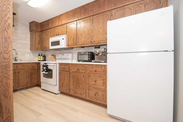 544 Auburn Pl NW Unit H, Elk River, MN 55330 - kitchen featuring white appliances, brown cabinets, light countertops, tasteful backsplash, and light wood-style floors