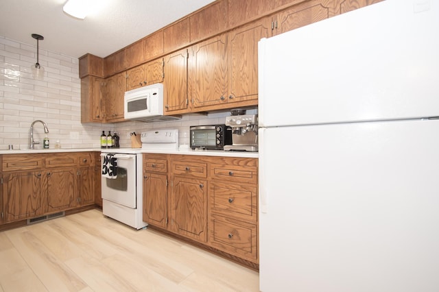 544 Auburn Pl NW Unit H, Elk River, MN 55330 - kitchen featuring white appliances, decorative backsplash, brown cabinets, and light countertops