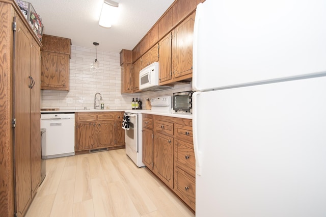 544 Auburn Pl NW Unit H, Elk River, MN 55330 - kitchen with white appliances, brown cabinets, decorative backsplash, light wood-style flooring, and a textured ceiling