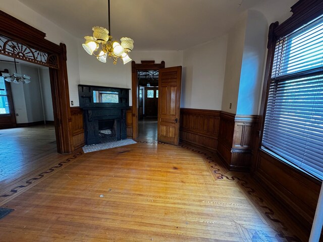 1601 Park Ave, Minneapolis, MN 55404 - unfurnished living room featuring a chandelier, wainscoting, light wood-style flooring, a fireplace with flush hearth, and wood walls
