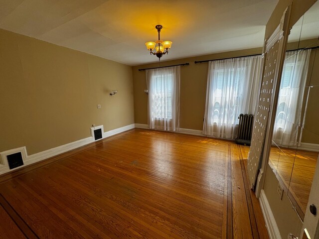 1601 Park Ave, Minneapolis, MN 55404 - empty room featuring wood finished floors, a chandelier, and radiator