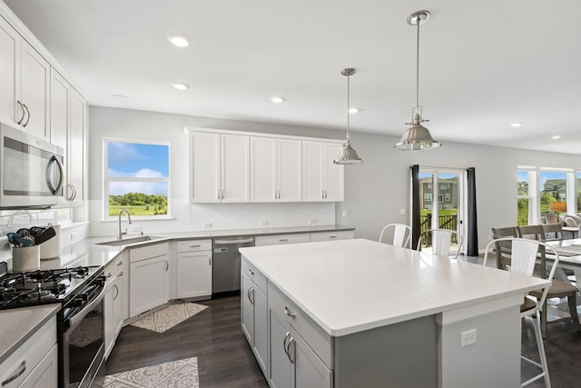 11604 Brayburn Trl, Dayton, MN 55369 - kitchen with appliances with stainless steel finishes, a breakfast bar area, a center island, tasteful backsplash, and dark wood-style flooring