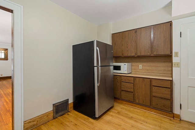 67 Lowry Ave NE, Minneapolis, MN 55418 - kitchen featuring freestanding refrigerator, white microwave, light countertops, and light wood-style flooring