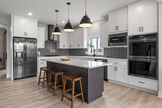 17660 Jett Cir, Prior Lake, MN 55372 - kitchen featuring appliances with stainless steel finishes, wall chimney range hood, a kitchen island, a breakfast bar area, and light countertops