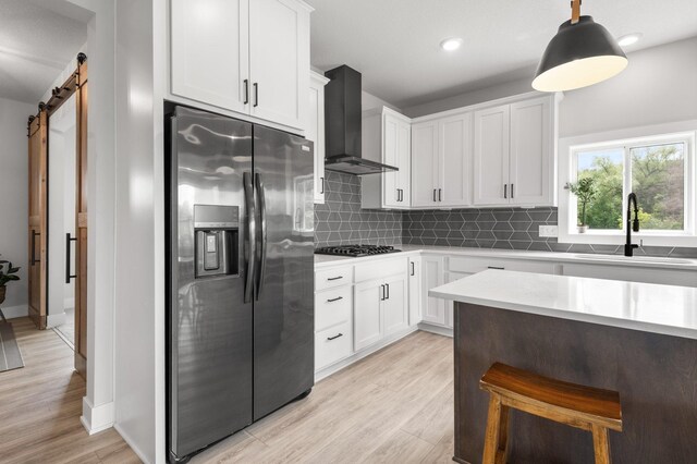 17660 Jett Cir, Prior Lake, MN 55372 - kitchen featuring stainless steel fridge with ice dispenser, wall chimney range hood, gas stovetop, a barn door, and tasteful backsplash
