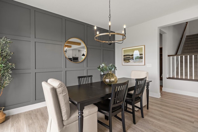 17660 Jett Cir, Prior Lake, MN 55372 - dining room featuring a decorative wall, a chandelier, stairs, and light wood-style floors