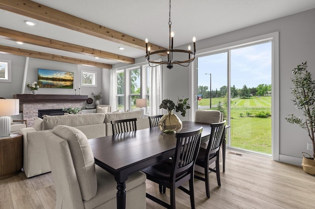 17660 Jett Cir, Prior Lake, MN 55372 - dining area with light wood finished floors, a chandelier, beamed ceiling, a stone fireplace, and golf course view