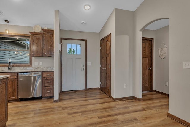 83 Meadow Ln, Cold Spring, MN 56320 - kitchen with dishwasher, arched walkways, light wood-style floors, baseboards, and light stone countertops