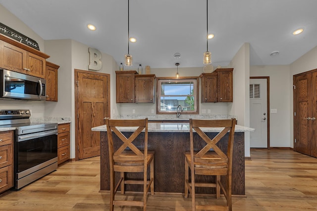83 Meadow Ln, Cold Spring, MN 56320 - kitchen featuring appliances with stainless steel finishes, light wood-style flooring, a kitchen bar, a sink, and decorative light fixtures
