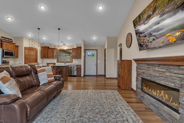 83 Meadow Ln, Cold Spring, MN 56320 - living area featuring a stone fireplace, dark wood finished floors, lofted ceiling, recessed lighting, and baseboards